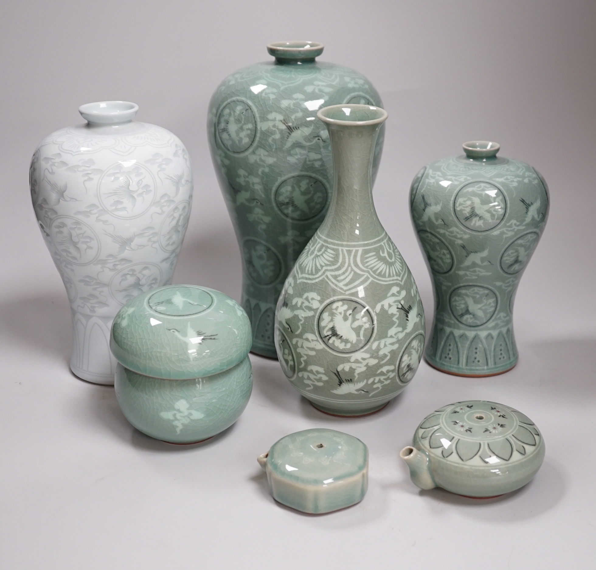 Seven pieces of Korean celadon glazed ceramics including four vases decorated with cranes amongst clouds, the largest 22cm high